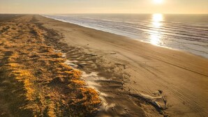 A beach with a clear path leading to the water, a sandy shore, and the ocean.
