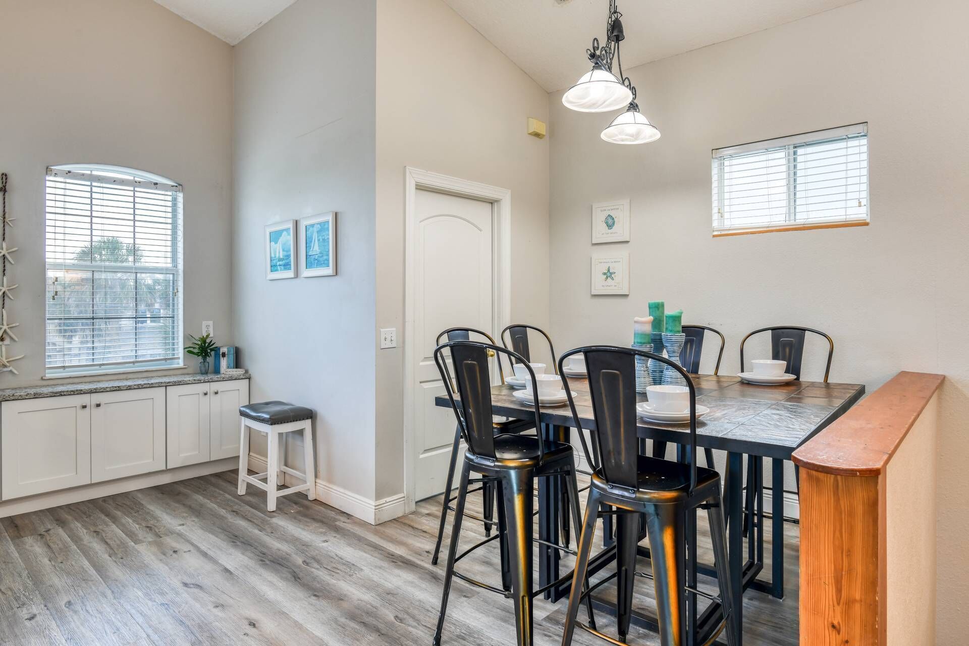 A dining area with a wooden table, black chairs, and a white door.