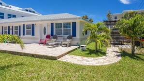 A house with a patio area featuring outdoor furniture and a small garden with palm trees.