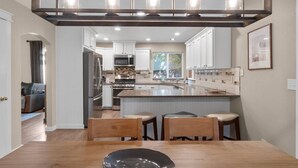 A modern kitchen with white cabinets, stainless steel appliances, and a central island.