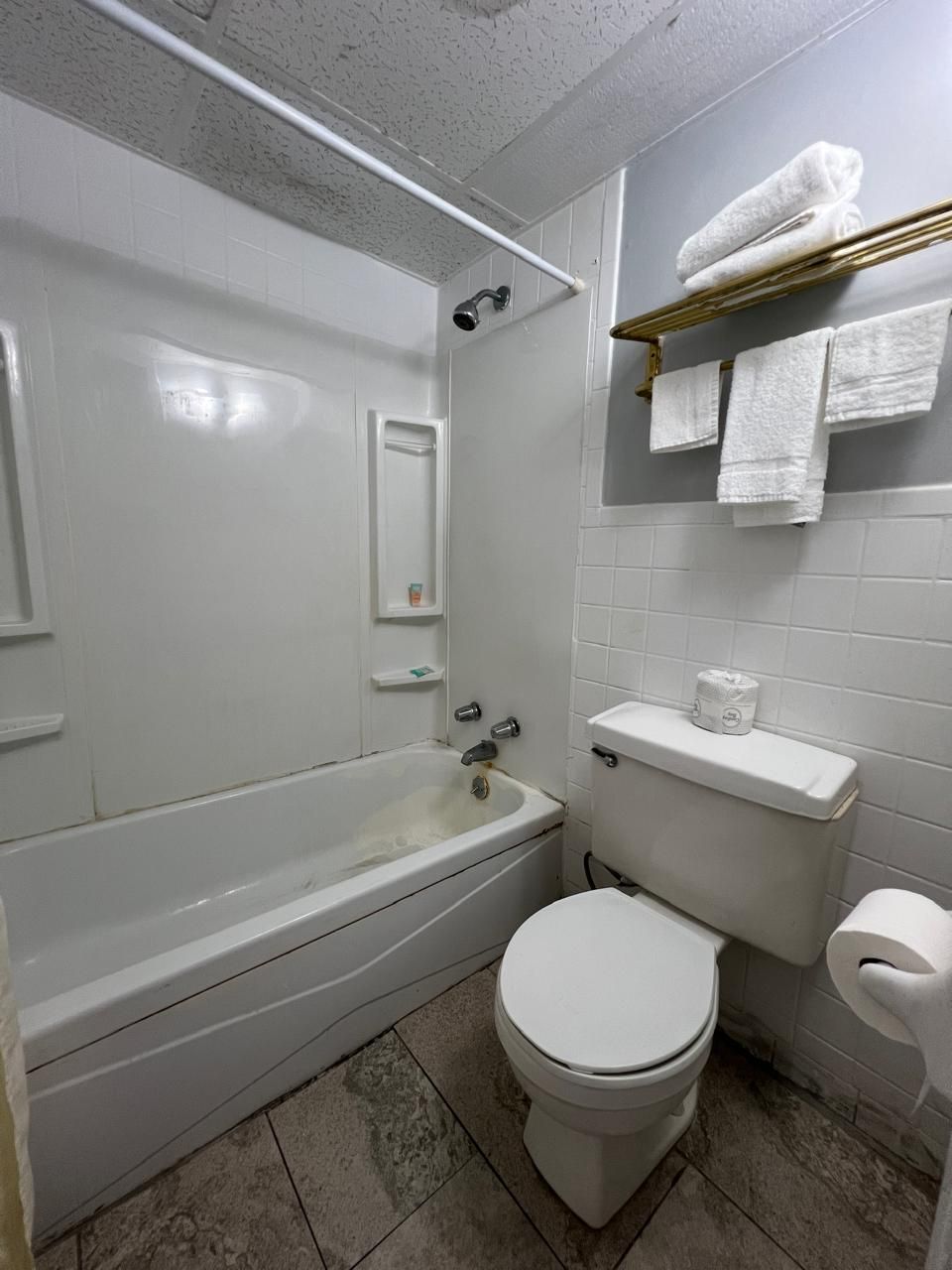 A bathroom with a bathtub, toilet, and a shelf with towels.