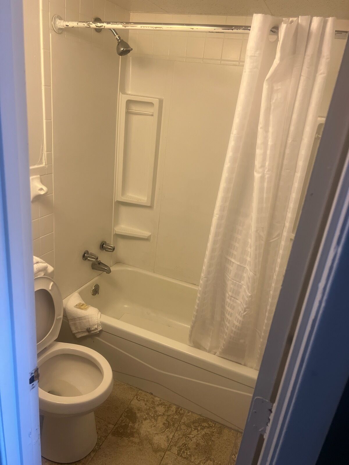 Une salle de bain avec une baignoire, des toilettes et un rideau de douche.
