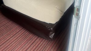 Een hotelkamer met twee eenpersoonsbedden, een groot bed, een vloerbedekking en twee ingelijste foto's aan de muur.