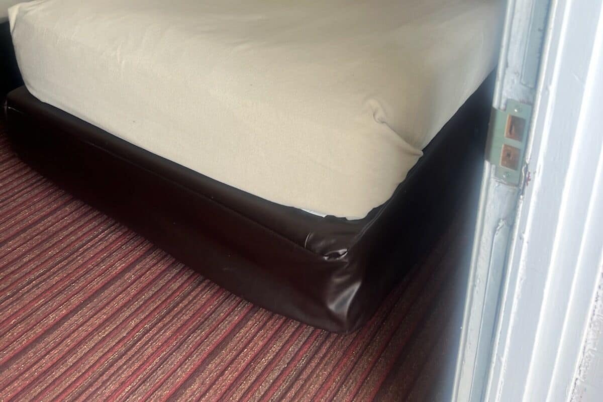 Ein Hotelzimmer mit zwei Einzelbetten, einem großen Bett, Teppichboden und zwei gerahmten Bildern an der Wand.