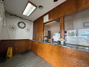 Een receptiegedeelte met een wand van houten panelen, een receptiebalie, een klok en een waarschuwingsbord op de vloer.
