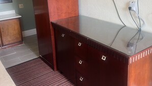 Een hotelkamer met een houten bureau, een flatscreen-tv aan de muur en een klein houten kastje.