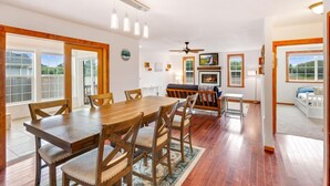 A dining area with a wooden table and chairs, a ceiling fan, and a fireplace.