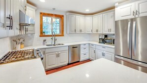 A modern kitchen with white cabinetry, stainless steel appliances, and a large island.