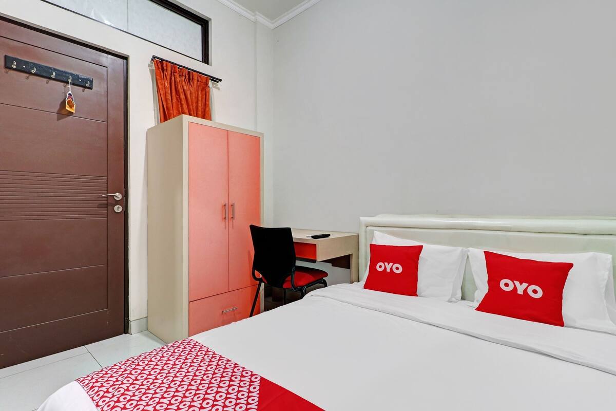 A hotel room with a bed, a desk, and a wardrobe.