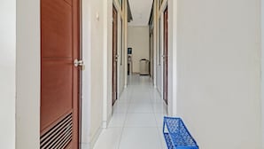 A corridor with doors on both sides, leading to a room at the end. - OYO 90452 Pillow Inn (Karawang)