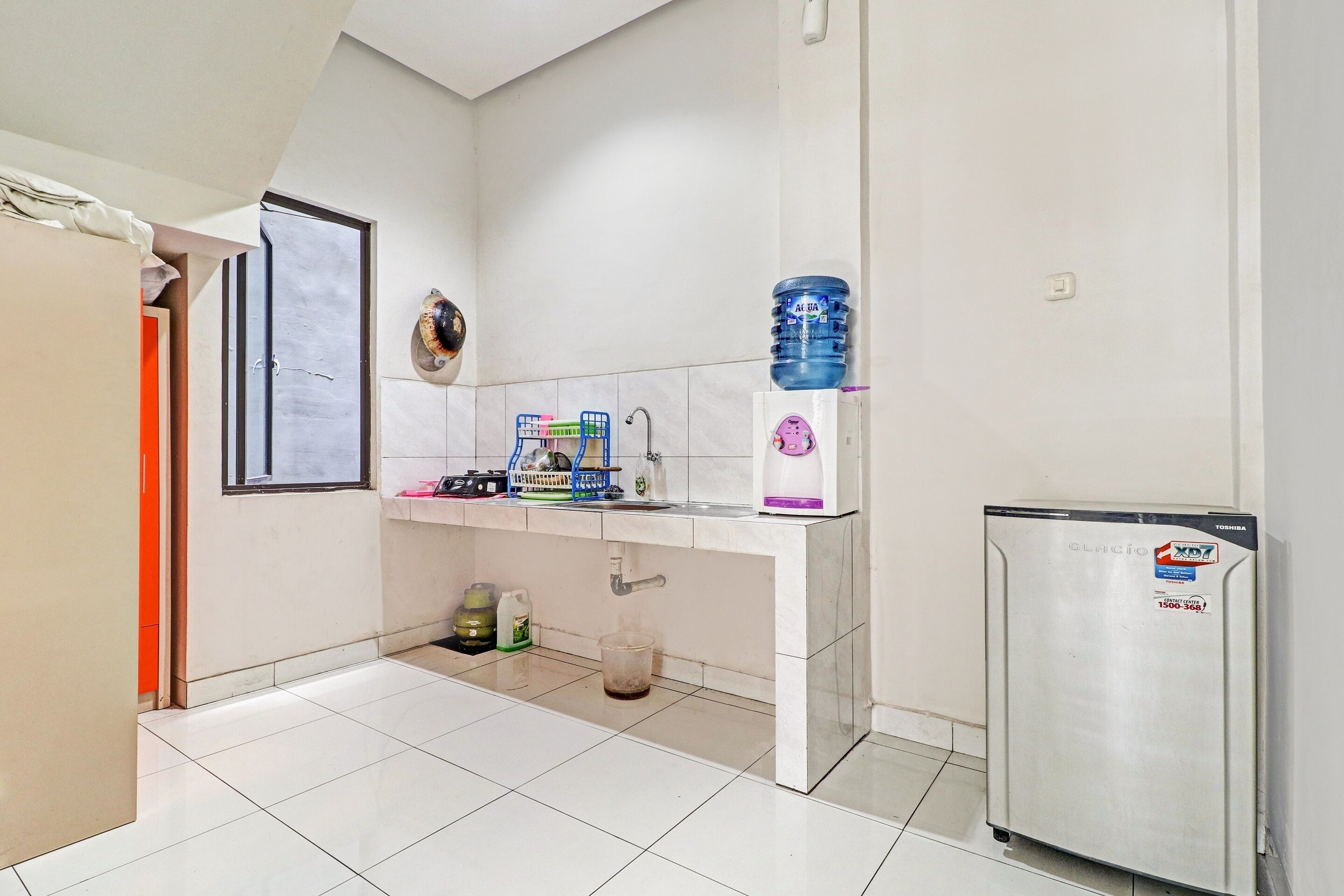 A kitchen with a white countertop, a refrigerator, a water dispenser, and a sink.