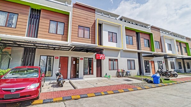 A modern residential building with multiple units, each featuring a balcony and a small front yard. - OYO 90452 Pillow Inn (Karawang)