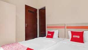 A hotel room with two beds, each with a red pillow labeled "OYO". - OYO 90452 Pillow Inn (Karawang)