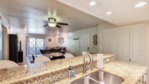 A modern kitchen with a granite countertop, stainless steel sink, and a ceiling fan. - Fantastic Location! Heated Pool, Close to Giants Stadium, Minutes from Old Town Scottsdale + Golfing (Scottsdale)