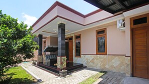A modern house with a covered porch, a potted plant, and a well-maintained lawn. - OYO 91777 Kemuning Guesthouse (Sempe)