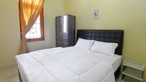 A neatly made bed with white bedding, a dark headboard, and a wardrobe with a glass door. - OYO 91777 Kemuning Guesthouse (Sempe)