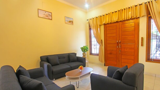 A living room with a sofa, two armchairs, a coffee table, and a potted plant. - OYO 91777 Kemuning Guesthouse (Sempe)