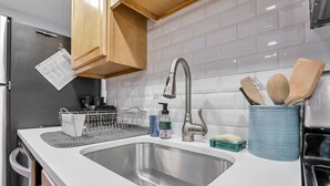 Una cocina moderna con un lavamanos de acero inoxidable, armarios de madera y un salpicadero de azulejos.