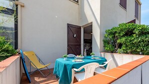 A small outdoor patio with a table set for two, a yellow chair, and a white chair. - Beautiful apartment for 3 guests with WIFI, TV and terrace (Le Barcarès)