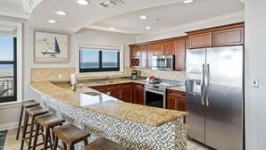 A kitchen with a large island, stainless steel appliances, and a view to the outside.
