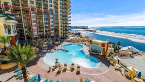 A hotel with a large pool, beach view, and multiple floors.