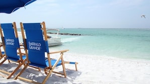 Beach chairs labeled 'Emerald Grande' and a boat in the background.