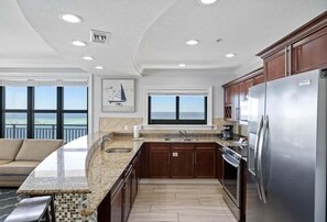 A kitchen with a large island, stainless steel appliances, and a view of the ocean.