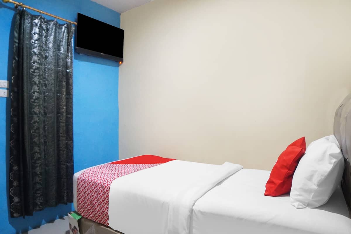 A room with a bed, a TV mounted on the wall, and a curtain.