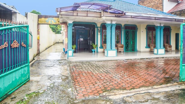 A building with a tiled roof, a covered porch with columns, and a gated entrance. - Hotel O Sky Residence Mawar (Medan)
