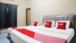 A hotel room with a large bed, a grey upholstered headboard, and three red pillows with the word "OYO" on them. - Hotel O Sky Residence Mawar (Medan)