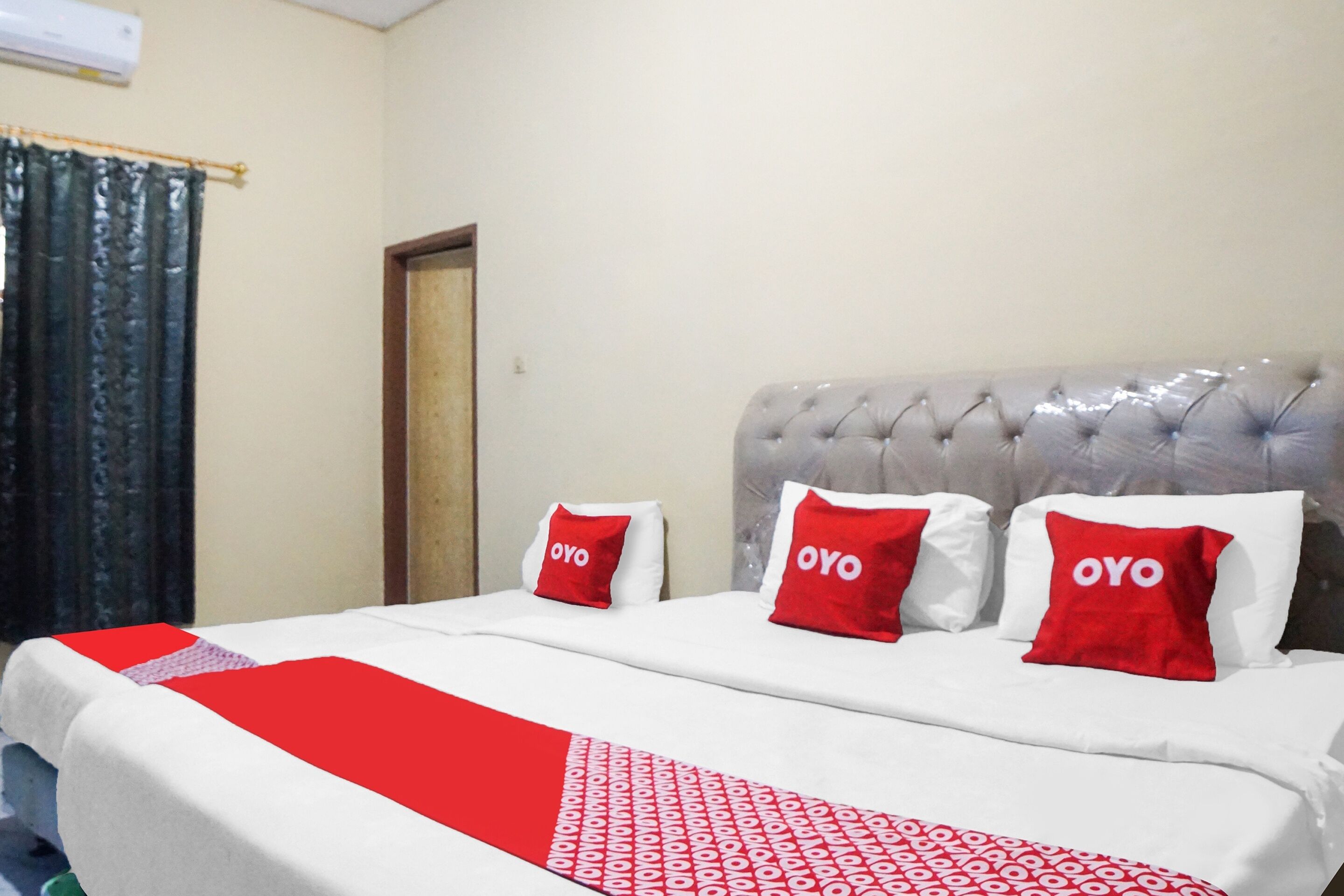 A hotel room with a bed, red pillows, and a red and white patterned blanket.