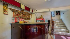 A staircase with a wooden handrail, a Coca-Cola refrigerator, and a decorative shelf with religious statues. - MeroStay 222 Guest House DD (Bhaktapur)