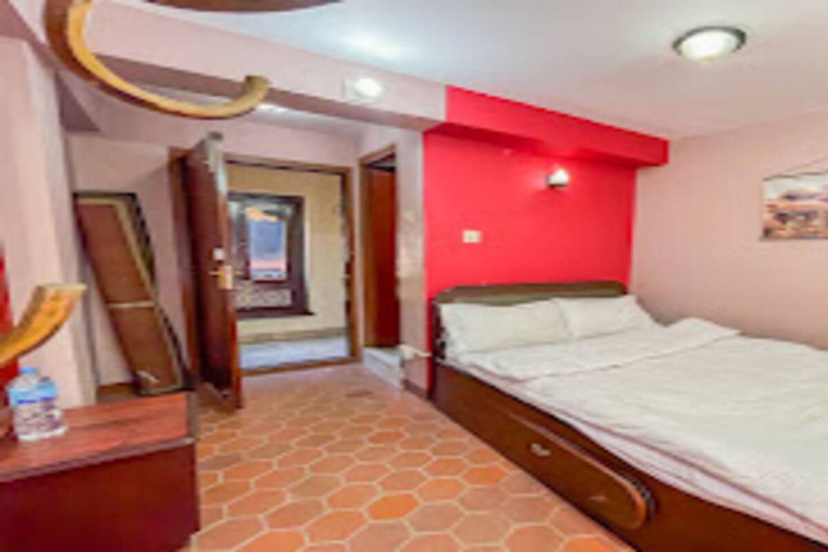 Une chambre à coucher avec un lit, un miroir, un mur d’accent de couleur rouge et une porte donnant sur une autre pièce.