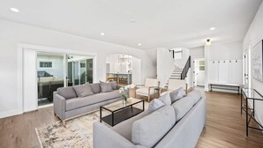 Un salon spacieux avec un canapé gris, une table basse et un escalier menant à l’étage supérieur.