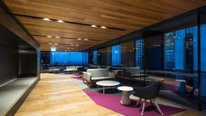 A modern lounge area with wooden flooring, glass walls, and seating arrangements including sofas and tables. - Simply Melbourne by Ready Set Stay - City Views, WIFI, full linen (Melbourne)
