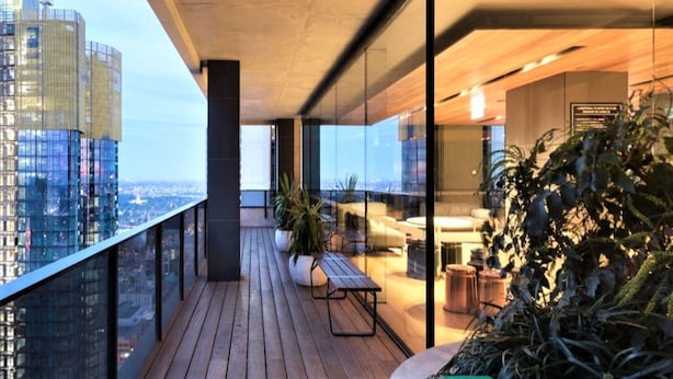 A modern balcony with a wooden floor, glass railings, and a seating area with a table and chairs. - Simply Melbourne by Ready Set Stay - City Views, WIFI, full linen (Melbourne)