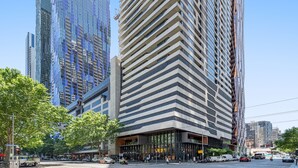 A modern urban street with high-rise buildings, a clear sky, and a mix of vehicles and pedestrians. - Simply Melbourne by Ready Set Stay - City Views, WIFI, full linen (Melbourne)