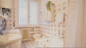 A bathroom with a toilet, sink, and shower area.