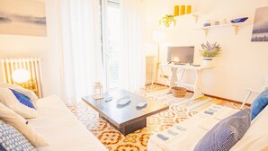 Un salon bien éclairé, avec un canapé, une table basse, un téléviseur et un radiateur.