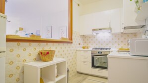 Une cuisine avec des meubles blancs, une cuisinière, un four et un four à micro-ondes.