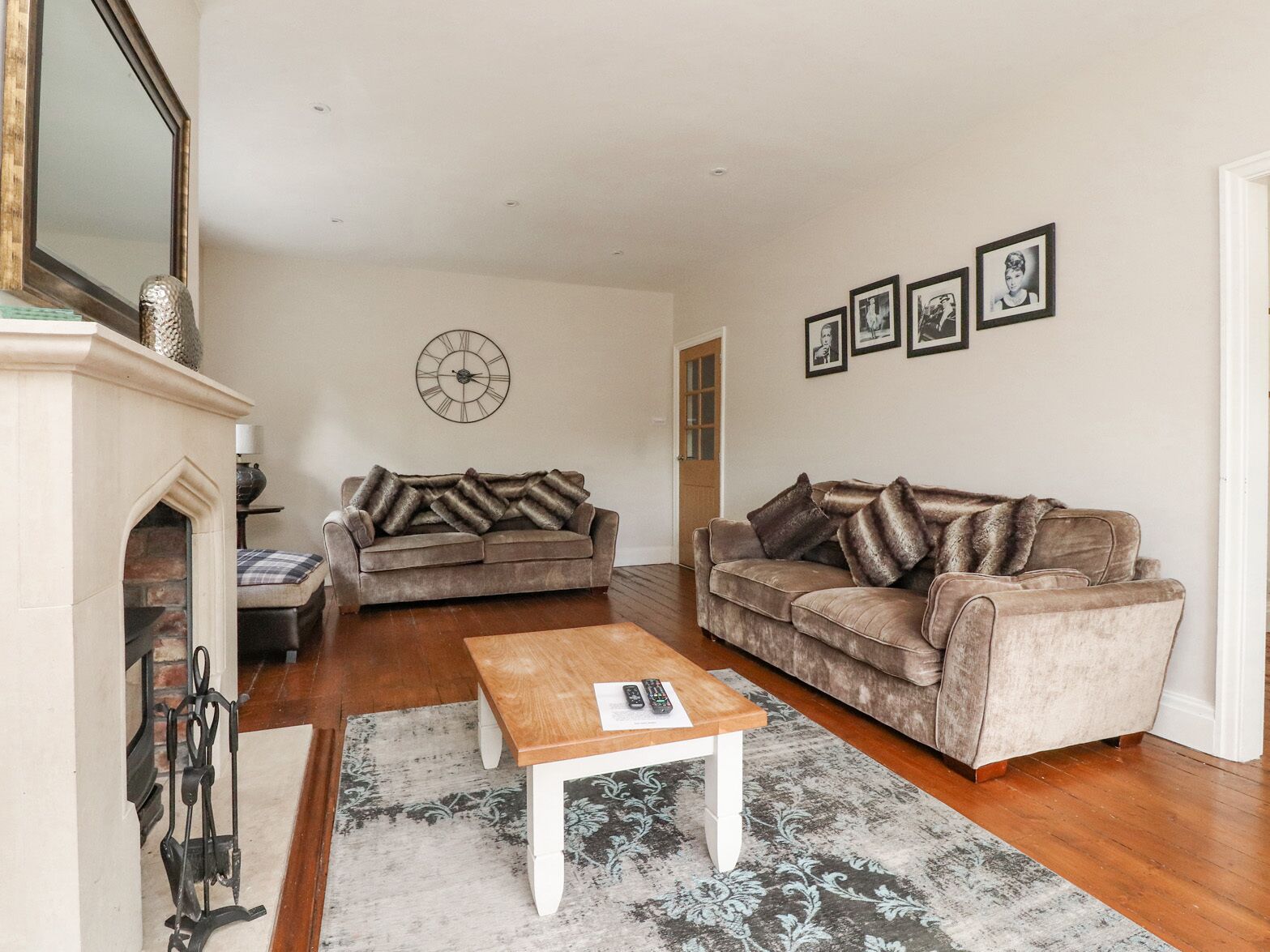 A living room with two sofas, a coffee table, a fireplace, and a clock on the wall.