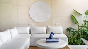 A modern living room with a sectional sofa, a round coffee table, and a large wall art piece. - Charming 1BR Villa w/ Pool | Green Flow Ubud (Ubud)