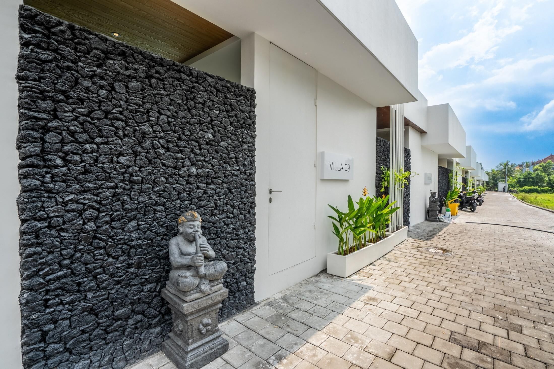 A modern building with a stone wall, a statue, and a sign reading 'Villa 09'.