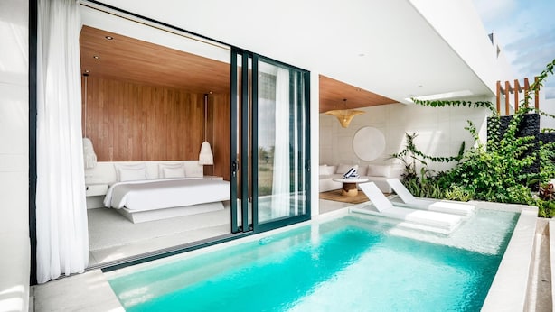 A modern poolside area with a clear view of a bedroom, a lounge chair, and a small table. - Charming 1BR Villa w/ Pool | Green Flow Ubud (Ubud)