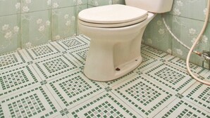 Un baño con inodoro, ducha y baldosas de suelo estampadas.