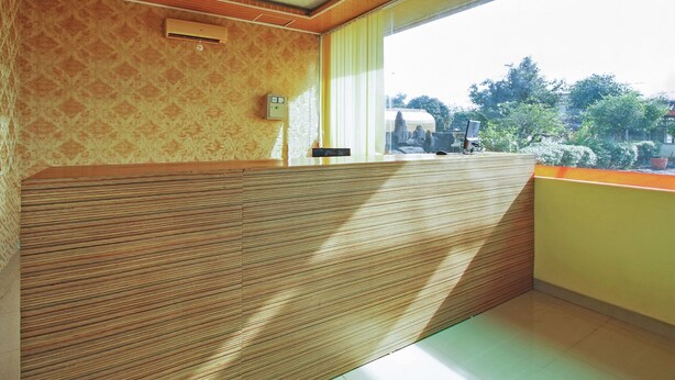 Una habitación con pared de paneles de madera, ventana con vista a follaje y techo con diseño de madera.