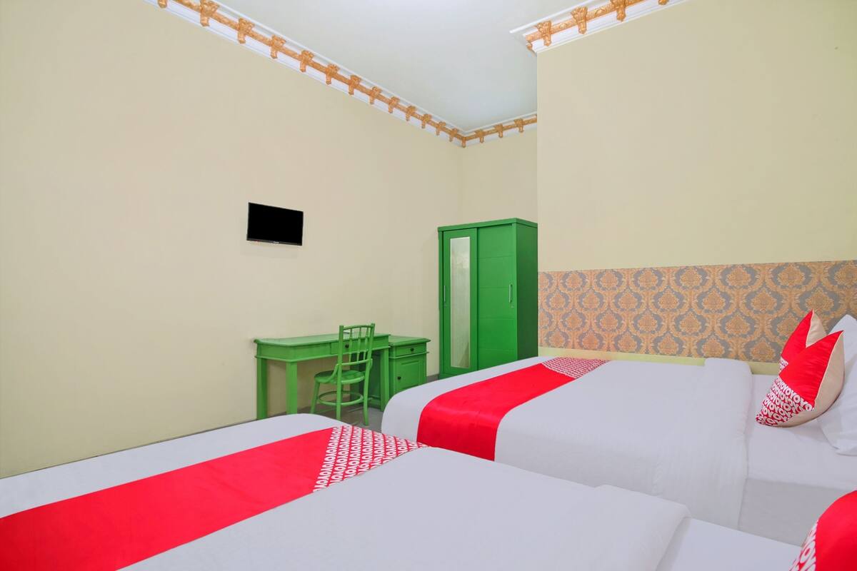 A hotel room with two beds, a desk, and a wardrobe.