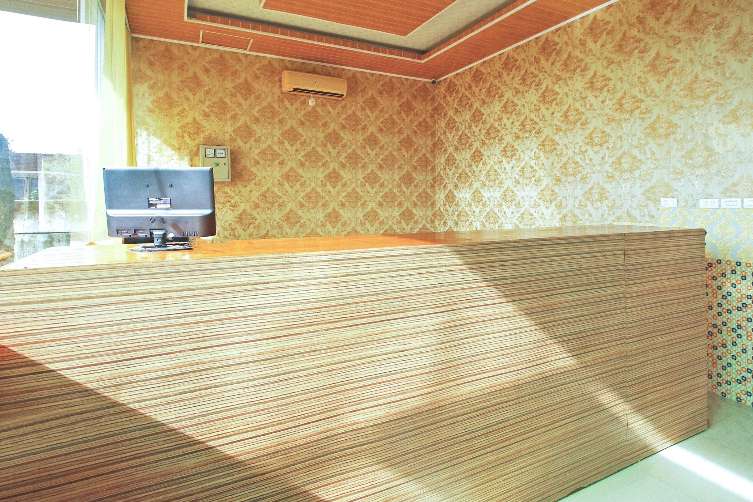 A reception desk with a patterned wallpaper and a wooden panel design.