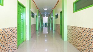 Un pasillo largo y estrecho con puertas verdes y paredes con diseños.