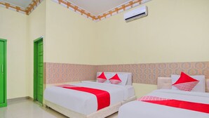 Habitación de hotel con dos camas, cada una con una colcha roja y blanca, y un diseño de pared estampado.